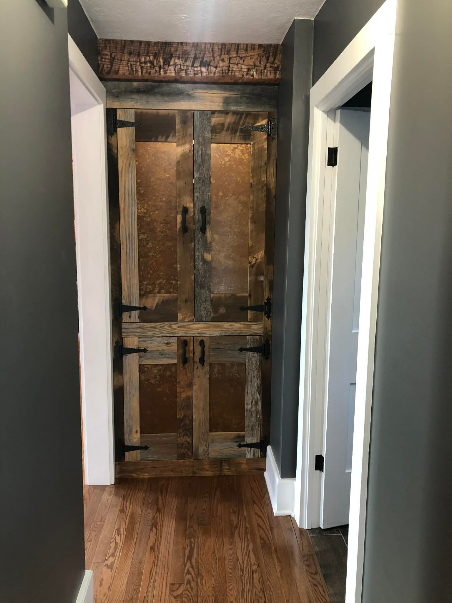 Rustic interior double door with mixed wood tones and strap hinges